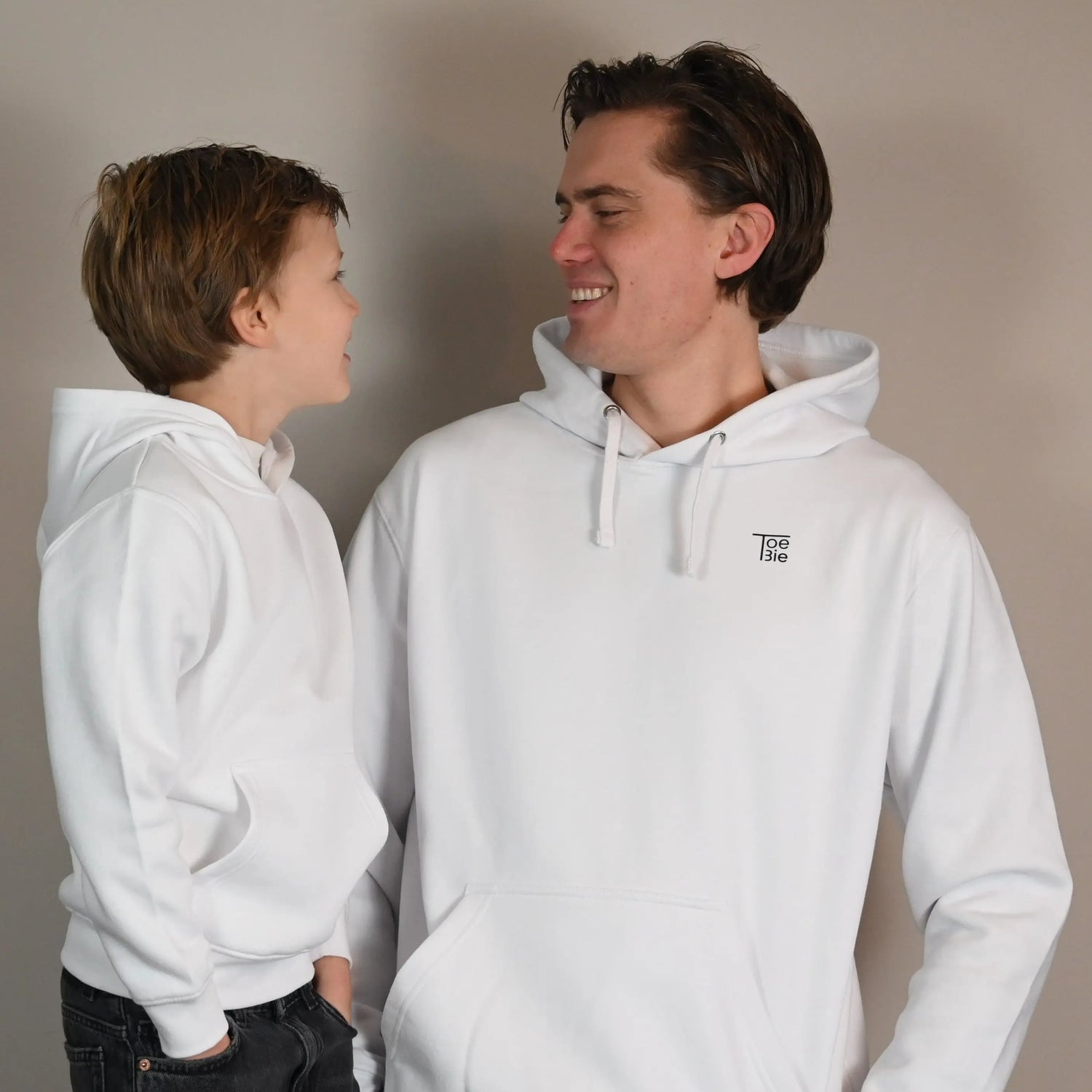 Vader en zoon dragen dezelfde hoodie, terwijl ze naar elkaar lachen