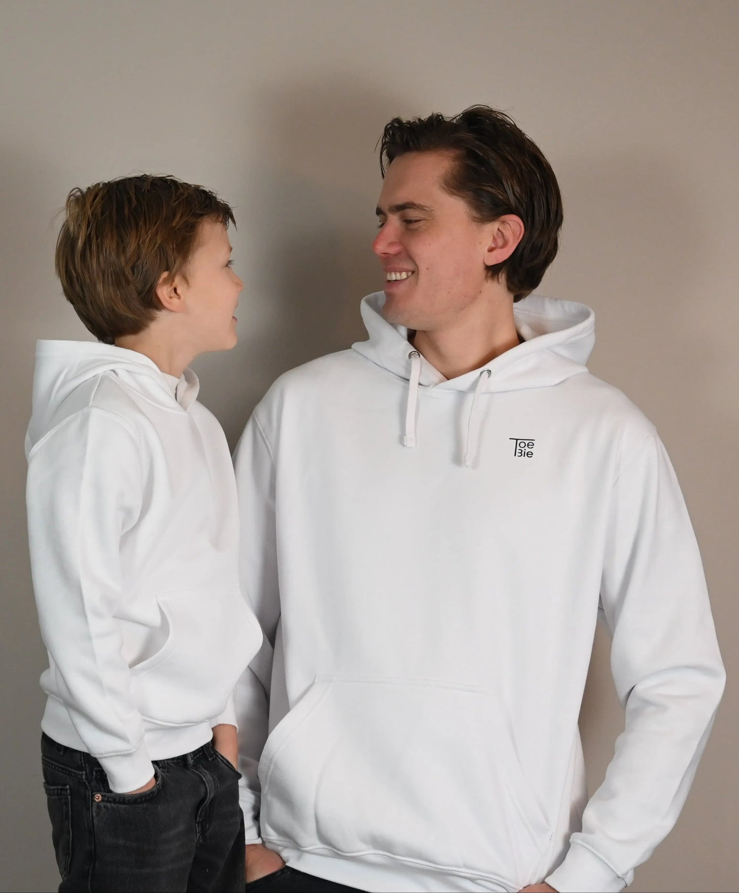 Vader en zoon dragen dezelfde hoodie, terwijl ze naar elkaar lachen