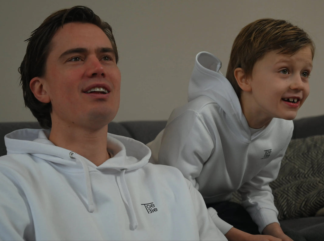 vader en zoon dragen dezelfde hoodie, terwijl ze aan het gamen zijn op de bank