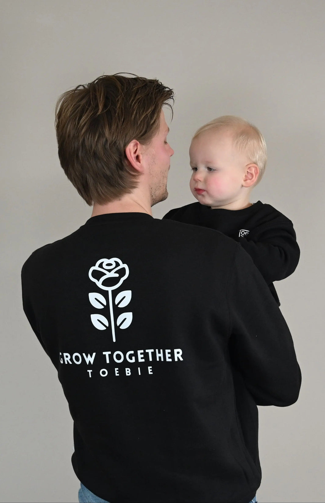vader en zoon dragen een matchende outfit, en poseren voor de foto waarbij de vader zijn rug toedraait