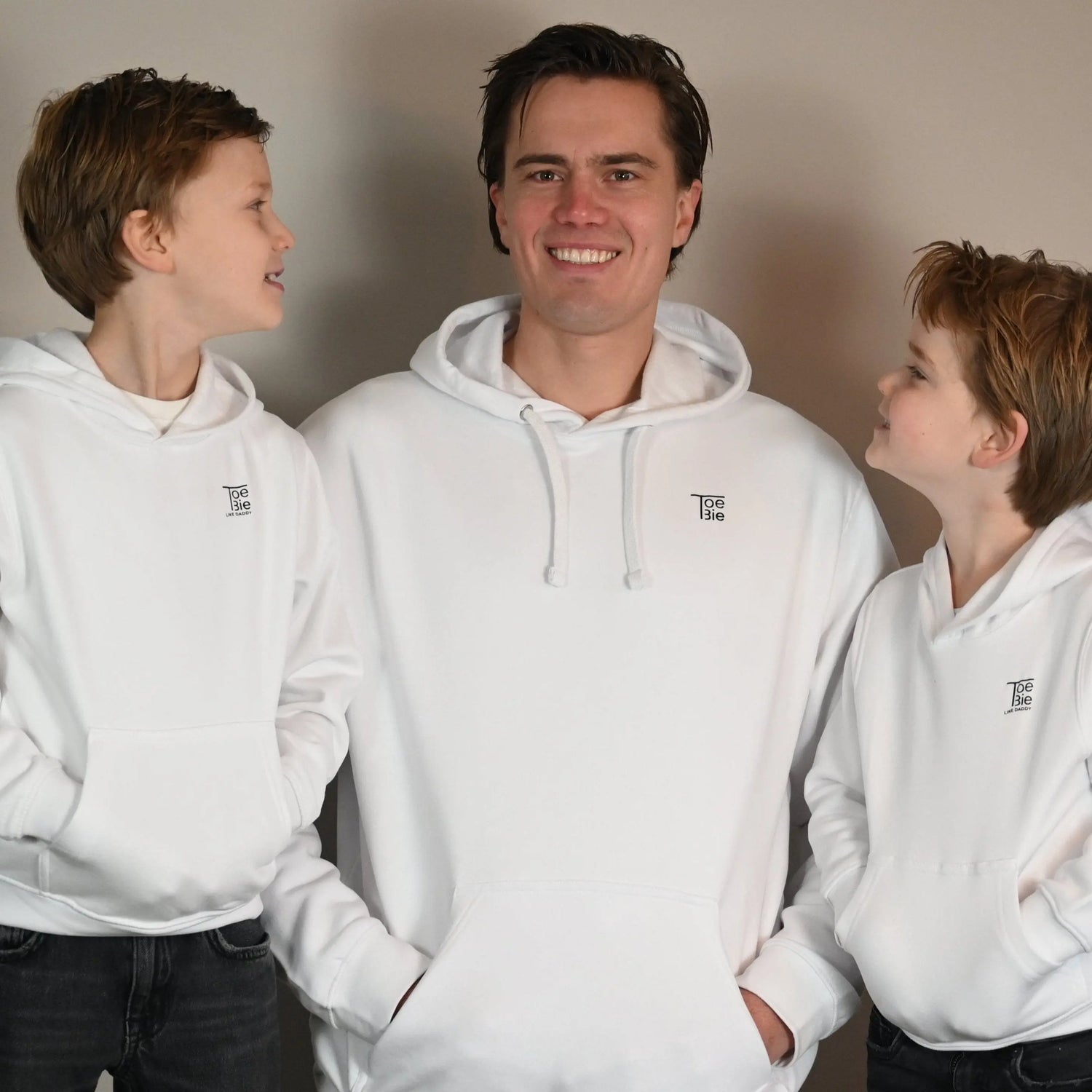 vader en zoon hoodie in het wit van toebie, vader en zoons staan lachend naast elkaar