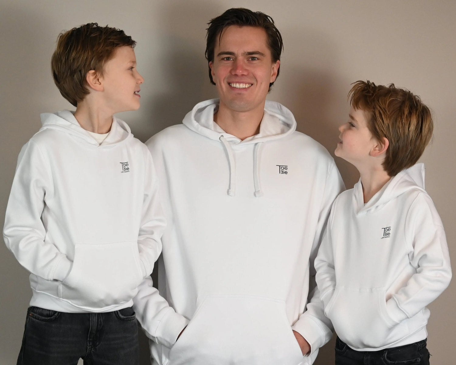 vader en zoon hoodie in het wit van toebie, vader en zoons staan lachend naast elkaar