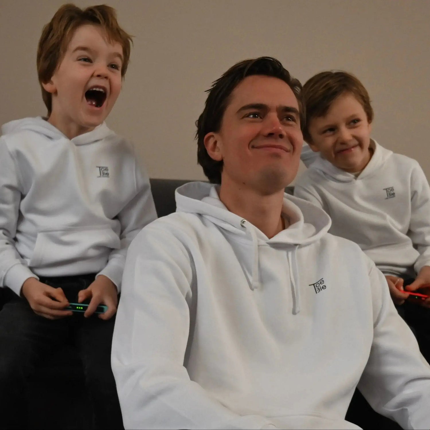 vader en zoon hoodie in het wit, ze zitten samen op de bank te gamen