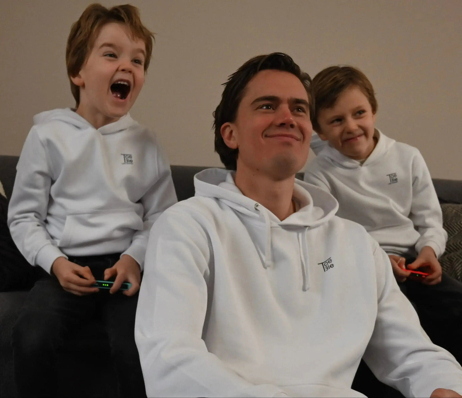 vader en zoon hoodie in het wit, ze zitten samen op de bank te gamen
