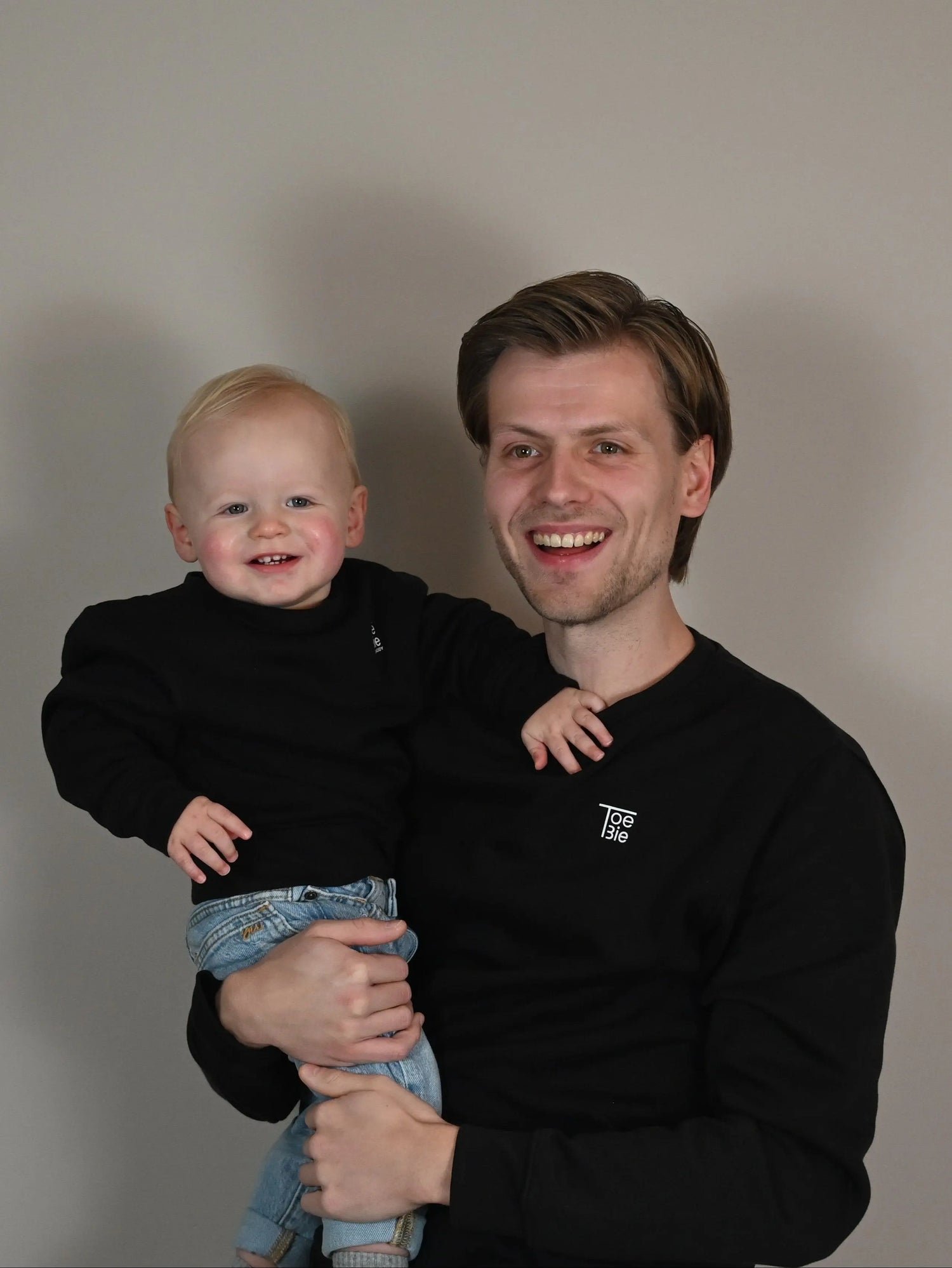 vader en baby dragen dezelfde sweater op de foto, waarop ze ook beiden lachen naar de camera