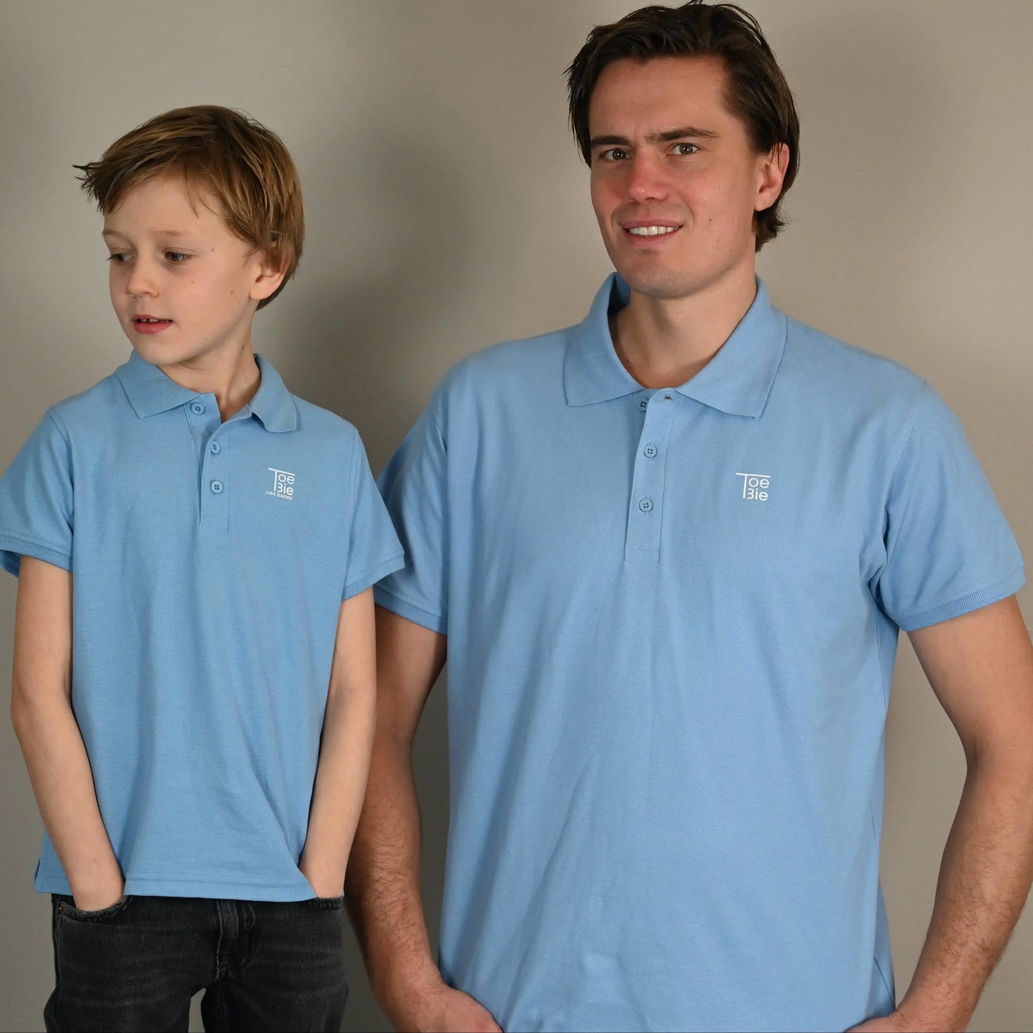 vader en zoon dragen een matchende polo terwijl ze naast elkaar poseren voor de foto
